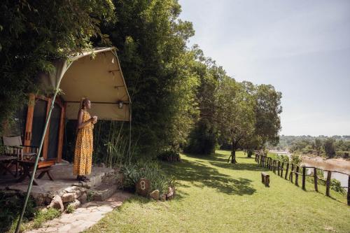 a woman standing in front of a house at Exploreans Mara River Camp in Musiara Campsite