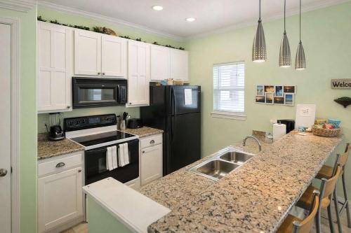 a kitchen with white cabinets and a black refrigerator at Los Cabos I #5 condo in South Padre Island