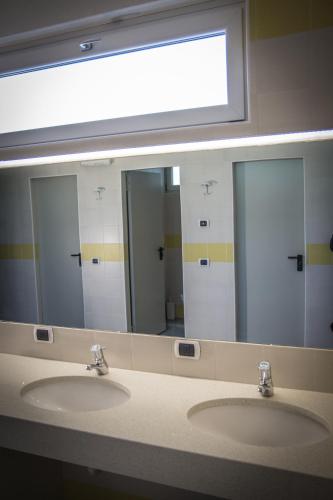a bathroom with two sinks and a large mirror at Sarca Lodge Val Rendena in Dare