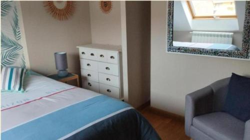 a bedroom with a bed and a chair and a mirror at Nuit etoile et jacuzzi prive in Pleuven