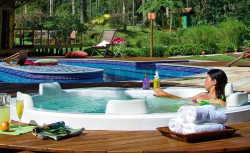 a woman sitting in a hot tub next to a pool at Pousada Villa Acauã in Visconde De Maua