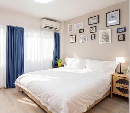 a bedroom with a large white bed with blue curtains at Home Story in Tokyo 江戸川区平井駅-上野 秋葉原まで直通 in Tokyo