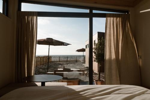 a bedroom with a bed and a view of the beach at Piatti beach suites in Zandvoort