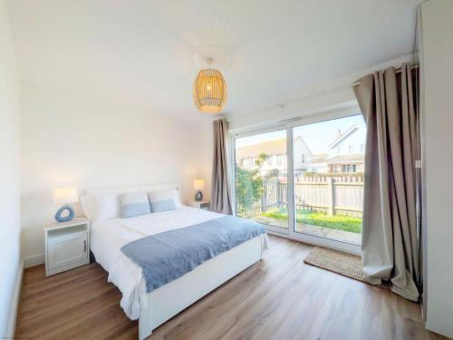 a white bedroom with a bed and a large window at The Beach Flat - Selsey in Selsey