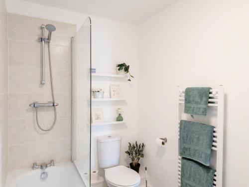 a white bathroom with a shower and a toilet at The Beach Flat - Selsey in Selsey