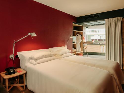 a bedroom with a white bed and a red wall at Casa Camper Berlin in Berlin