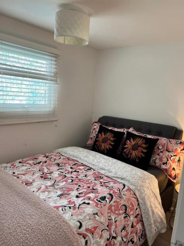 a bedroom with a bed with a flowered blanket and a window at Leysdown Beach Escape in Sheerness