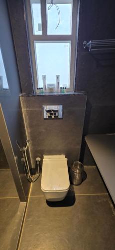 a bathroom with a toilet and a window at Hotel Sanskar Elite By Keshav Global in Jaipur