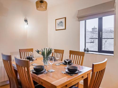 a dining room table with chairs and a large window at The Coach House in Kettlewell