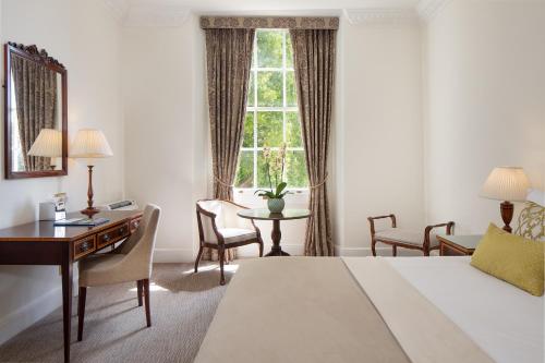 a hotel room with a bed and a desk and a window at Taplow House Hotel & Spa in Maidenhead