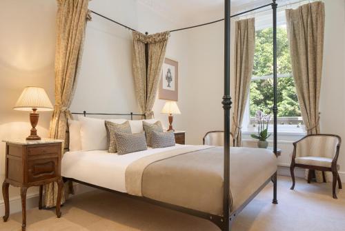 a bedroom with a four poster bed and a window at Taplow House Hotel & Spa in Maidenhead