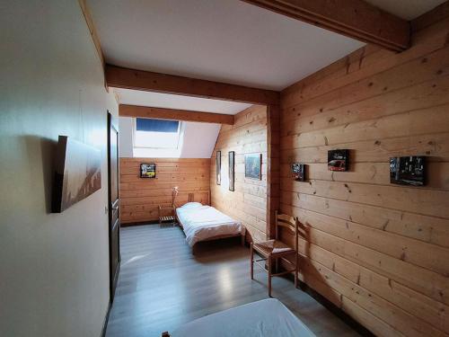 a room with two beds in a room with wooden walls at Aux Gîtes d'Orient in Géraudot