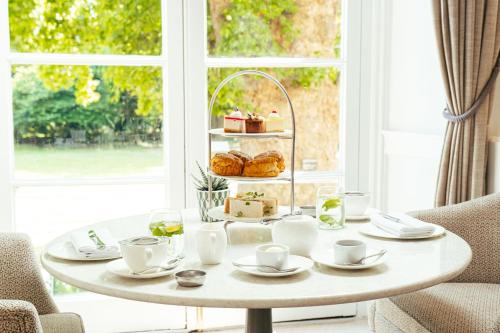 a white coffee table with pastries on it in front of a window at Taplow House Hotel & Spa in Maidenhead