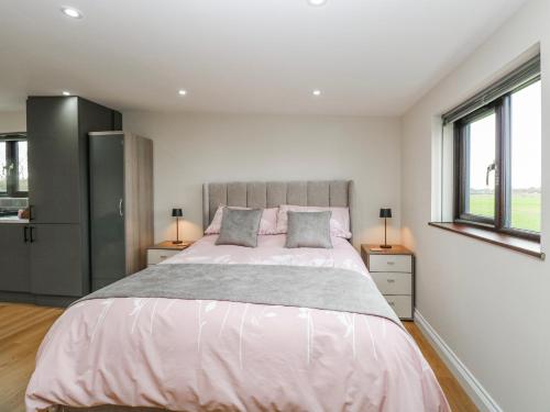 a bedroom with a large bed and two windows at Aloe Lodge in Diss