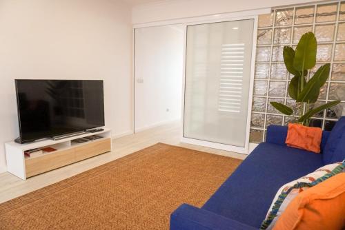 a living room with a blue couch and a tv at South Shore 1 - HOST & CHILL in São Roque