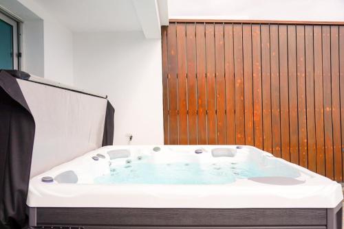 a bath tub in a bathroom with a wooden wall at South Shore 1 - Jacuzzi - HOST & CHILL in São Roque