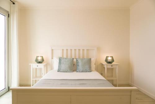 a bedroom with a white bed with two night stands at South Shore 1 - Jacuzzi - HOST & CHILL in São Roque