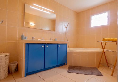 a bathroom with a blue cabinet and a tub and sink at Les Cannes Trankil in Saint-Louis