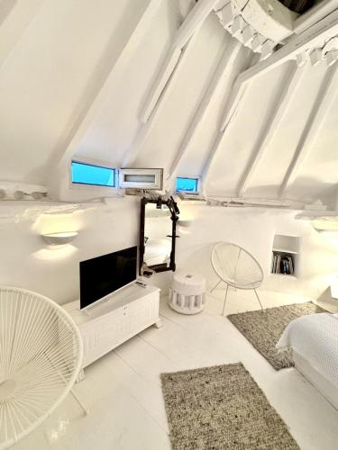 a living room with white furniture and a flat screen tv at Windmill of Mykonos in Mikonos
