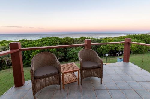 two chairs and a table on a balcony with the ocean at White Waves on the Beach in Hastings Point