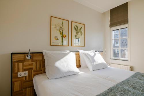 Twee bedden in een slaapkamer met witte lakens en kussens. bij Hotel Bleecker by BHC in Bloemendaal