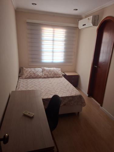 a bedroom with a bed and a table and a window at Suíte até 3 pessoas, Centro, Piscina in Foz do Iguaçu
