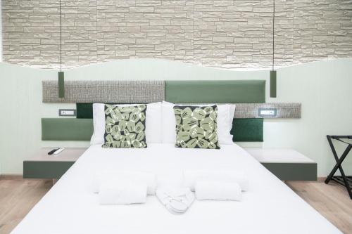 a bedroom with a white bed with green and white pillows at Giulio Cesare Luxury Rooms in Rome