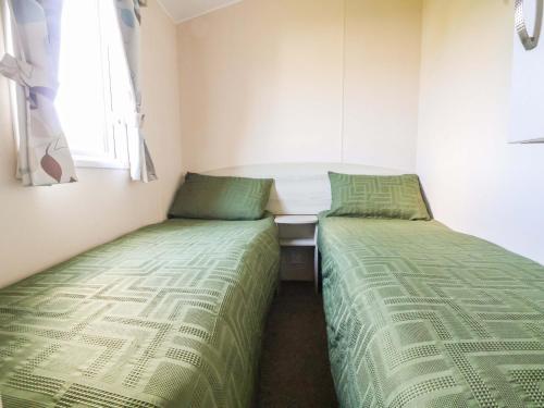 a bedroom with two beds and a table and a window at Dunes View in Prestatyn
