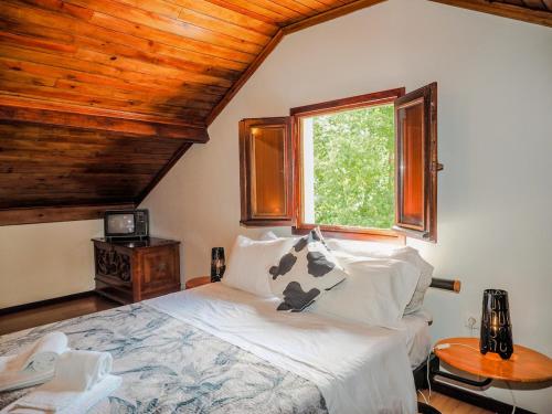 a bedroom with a large bed with a window at Casa do Batoco in Vieira do Minho