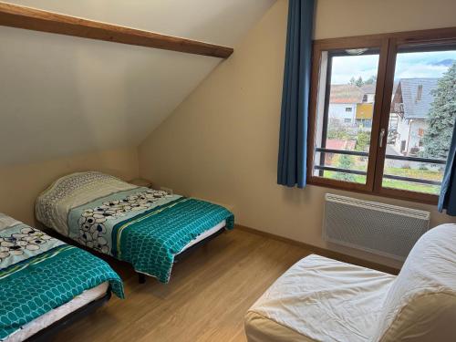 two beds in a room with a window at F ou d'Lac in Doussard