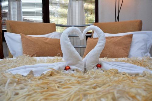 two white swans making a heart shape on a bed at Momini Dvori Boutique Guest House in Bansko