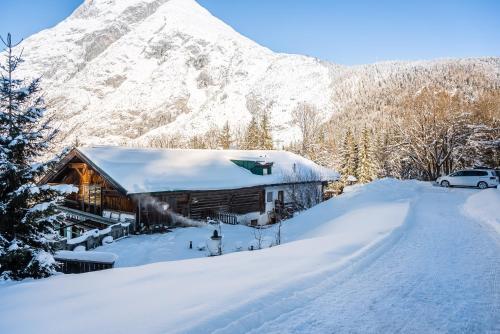 a cabin in the snow with a snow covered mountain at Ropferhof in Telfs-Buchen