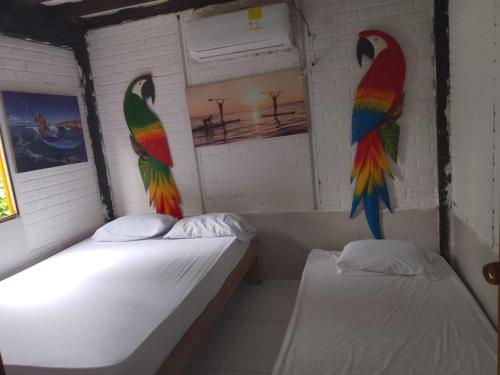 zwei Betten in einem Zimmer mit Pfauen an der Wand in der Unterkunft Kokomo in Coveñitas