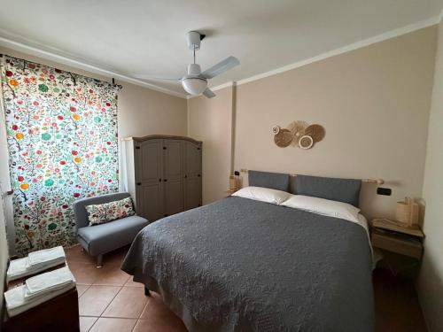 a bedroom with a bed and a chair and a window at La Corte di San Rocco in Murazzano