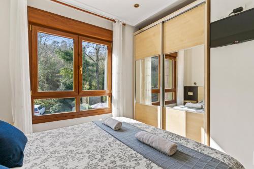 a bedroom with a bed and a large window at Apartamentos Rurales & Spa Antilles Playa in Llanes