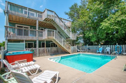 a house with a swimming pool and chairs and a house at 3215 - Papa Duck in Duck