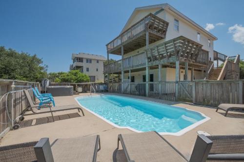 a swimming pool with chairs and a house at 3218 - Swab The Duck in Duck