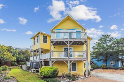a yellow house with a balcony on top of it at 3675 - Seaducktion in Duck