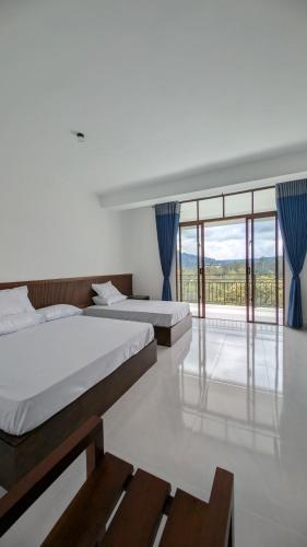two beds in a room with a large window at Ophelia in Diyatalawa