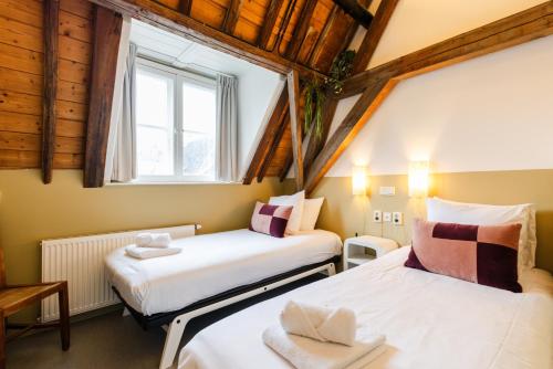 two beds in a small room with a window at Brass Hotel in Utrecht