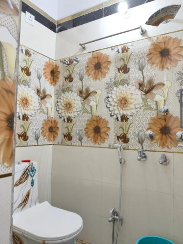 a bathroom with a toilet and flowers on the wall at Rupali Guest House in Patna