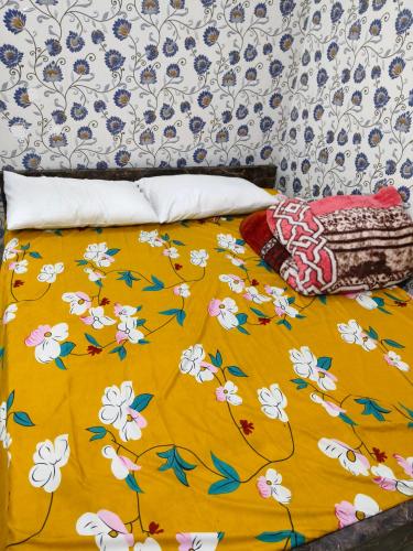 a bed with a yellow blanket with flowers on it at Rupali Guest House in Patna
