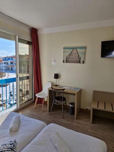 a hotel room with a bed and a desk and a balcony at Hotel de la Plage - Barcares in Le Barcarès