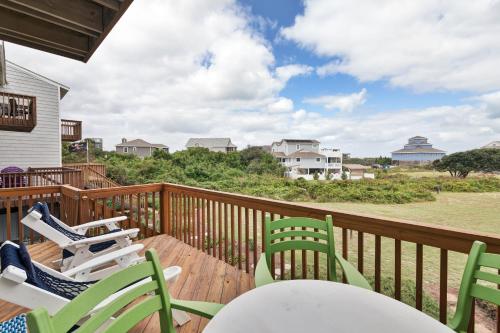 a deck with chairs and tables and a view of the beach at 4209 - Moby Duck in Duck