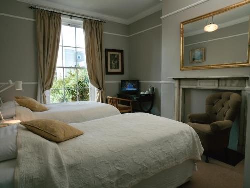 a bedroom with two beds and a mirror and a chair at Harveys Guest House in Dublin