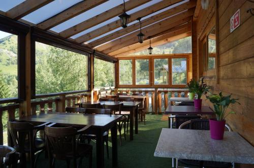 une salle à manger avec tables, chaises et fenêtres dans l'établissement Le Domaine du Trappeur, à Saint-Sorlin-dʼArves