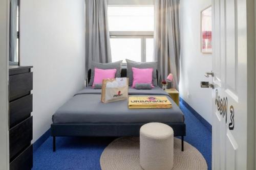 a bedroom with a bed with pink pillows and a stool at UrbanKey Studios - Vienna Neubau in Vienna