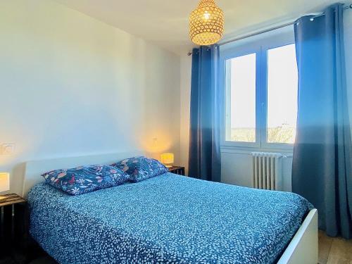 een slaapkamer met een blauw bed en een raam bij l'ESCAPADE TRANQUILLE in Rodez