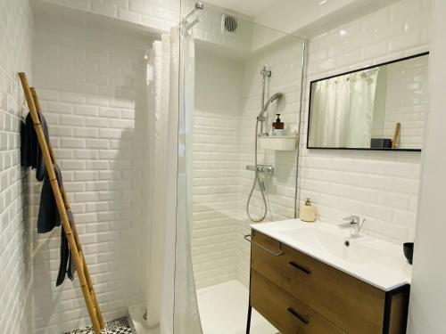 een witte badkamer met een douche en een wastafel bij l'ESCAPADE TRANQUILLE in Rodez