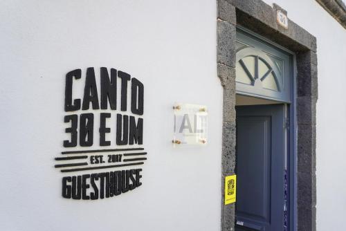 a sign on the side of a building with a door at Canto 30 e UM - HOST & CHILL in Ribeira Grande